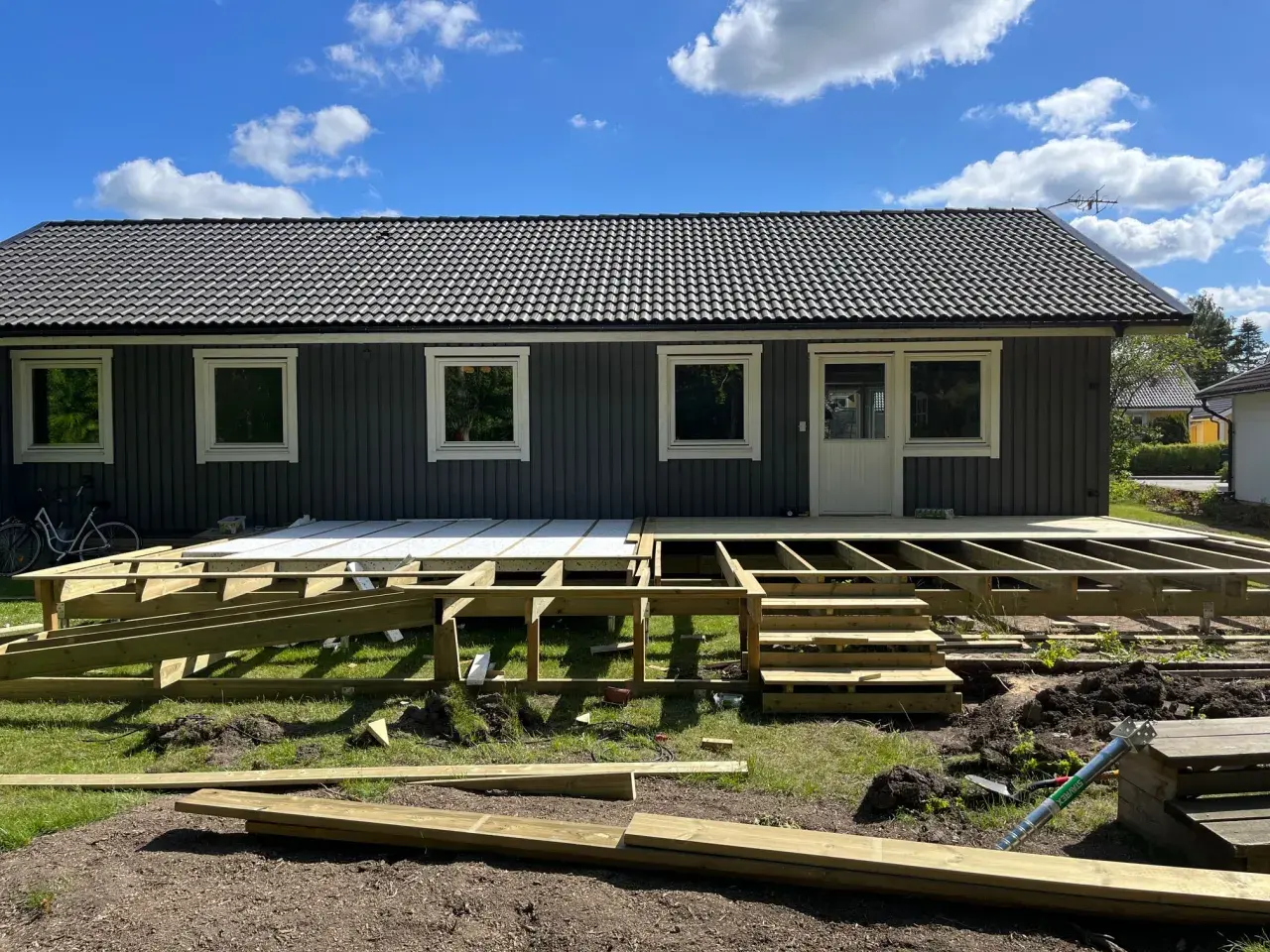 Grundarbete för att bygga veranda. Träkonstruktion och trappor på plats framför huset.
