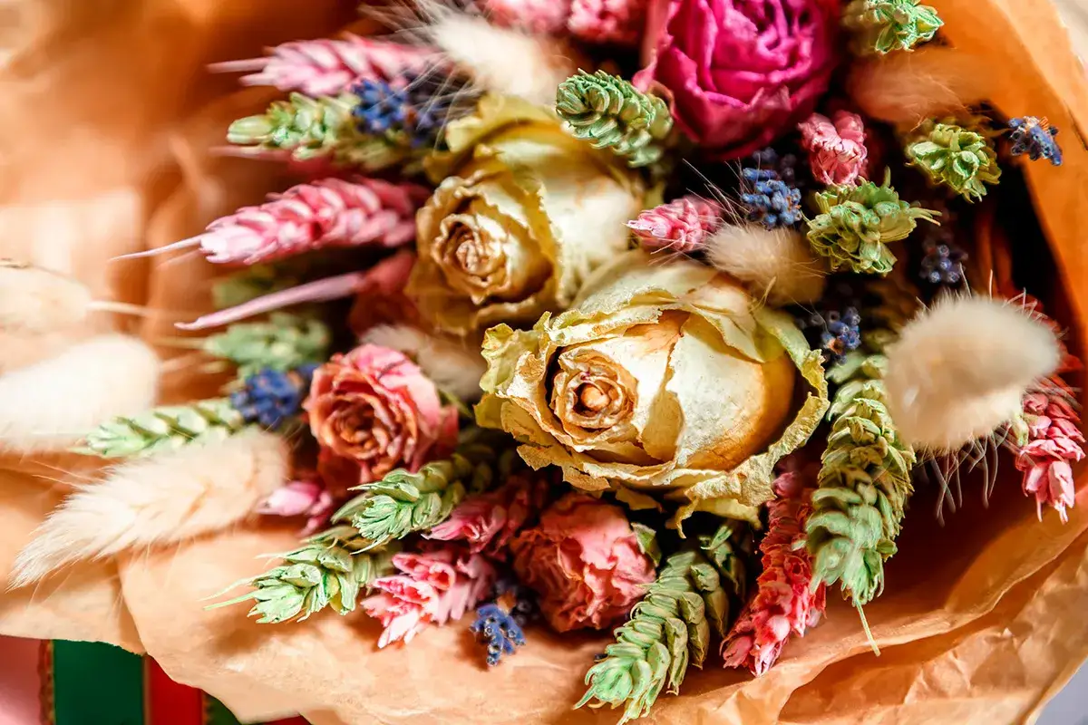 En bukett med torkade rosor och andra blommor i mjuka färger, som skapar en tidlös och romantisk känsla.